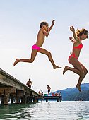 zwei Kinder die von einem Steg in den See hüpfen